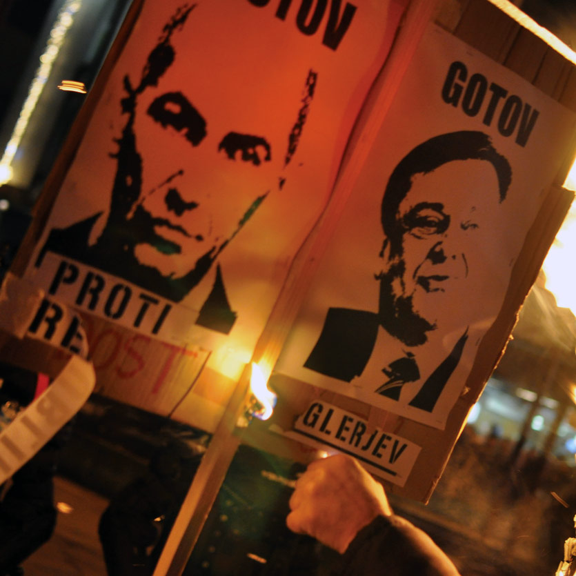 a portly politician talks into a bouquet of press microphones that surround him